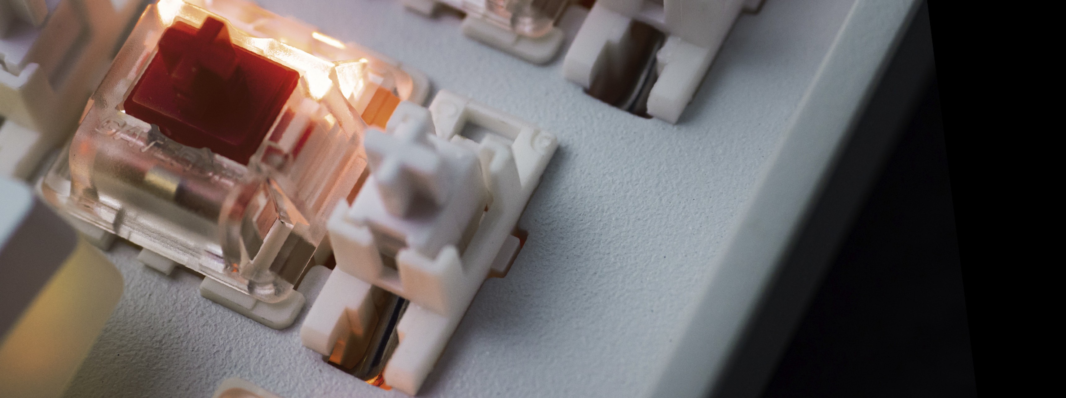 Close-up of a mechanical keyboard with illuminated switches and a white casing.