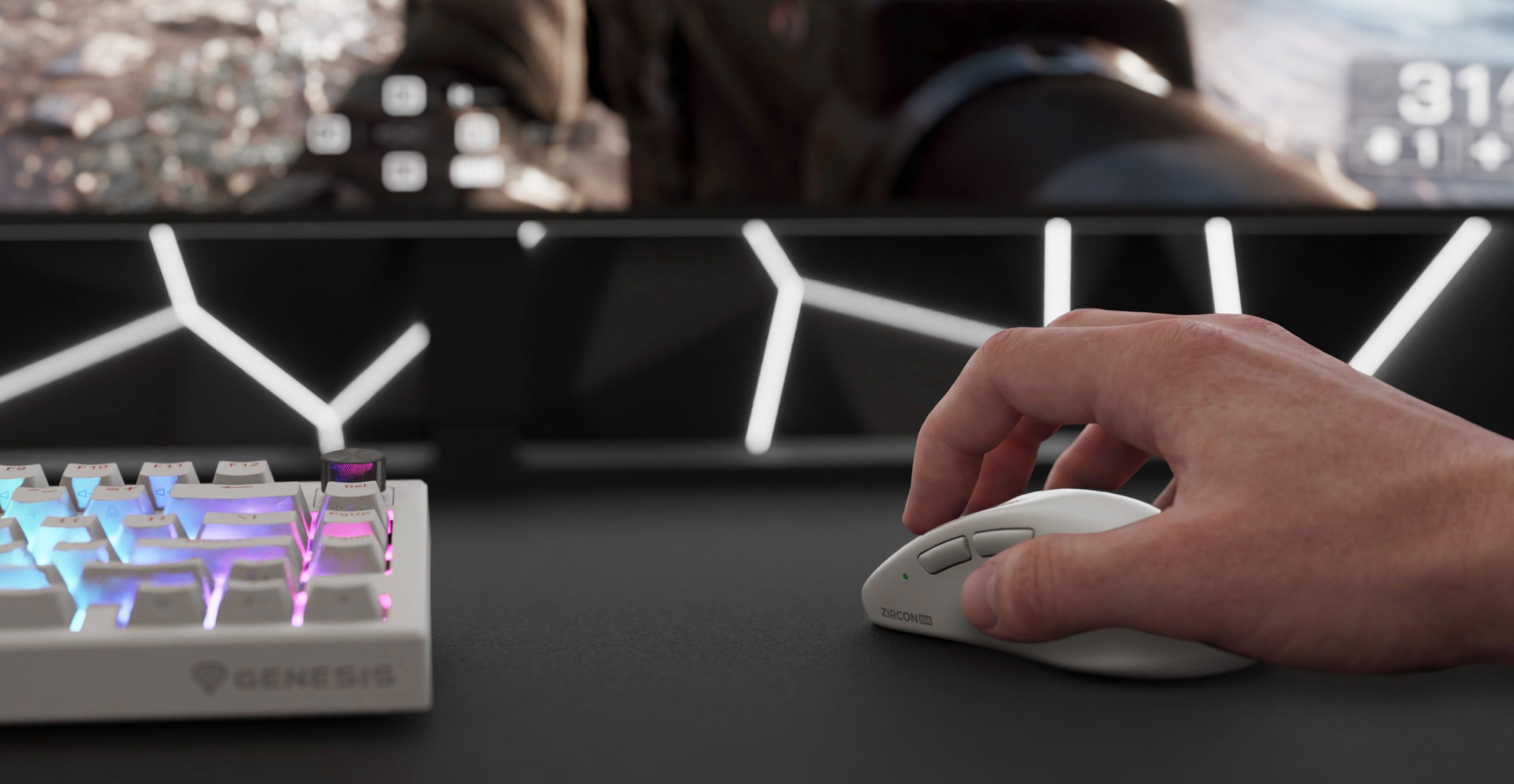 A hand using a computer mouse next to a keyboard with colored lights and a monitor in the background.