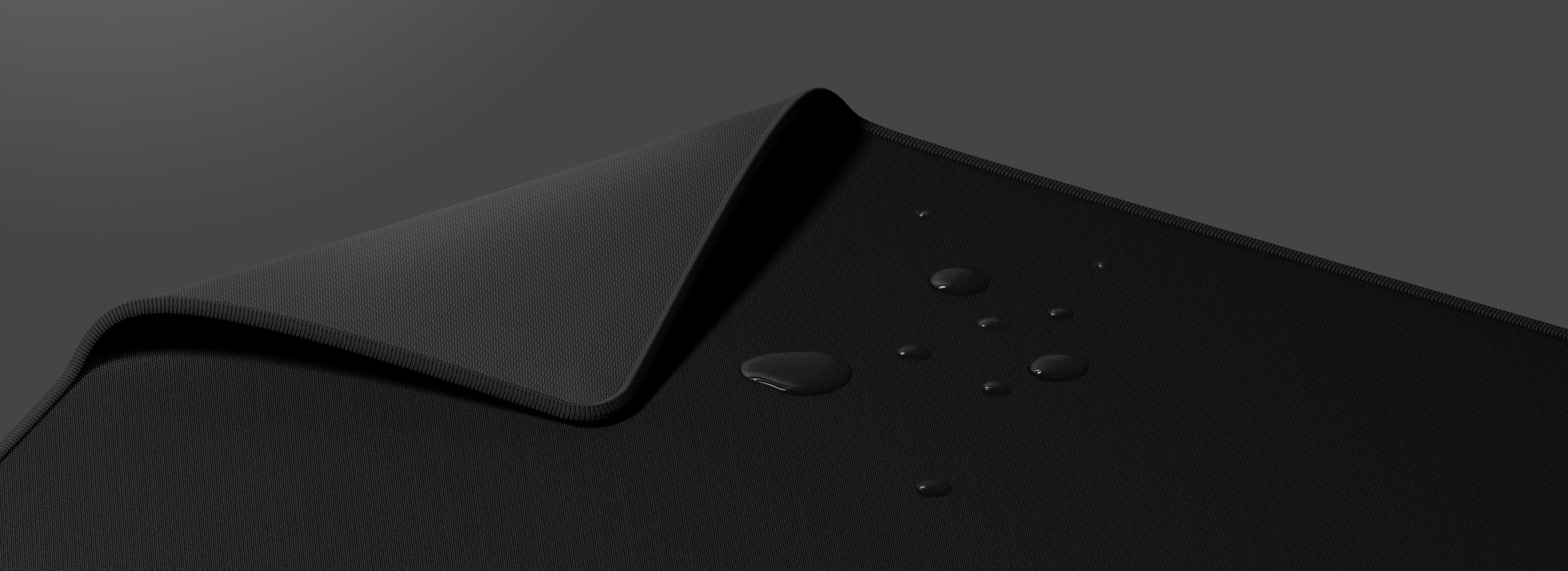 Black mouse pad with a textured surface and droplets of liquid on it