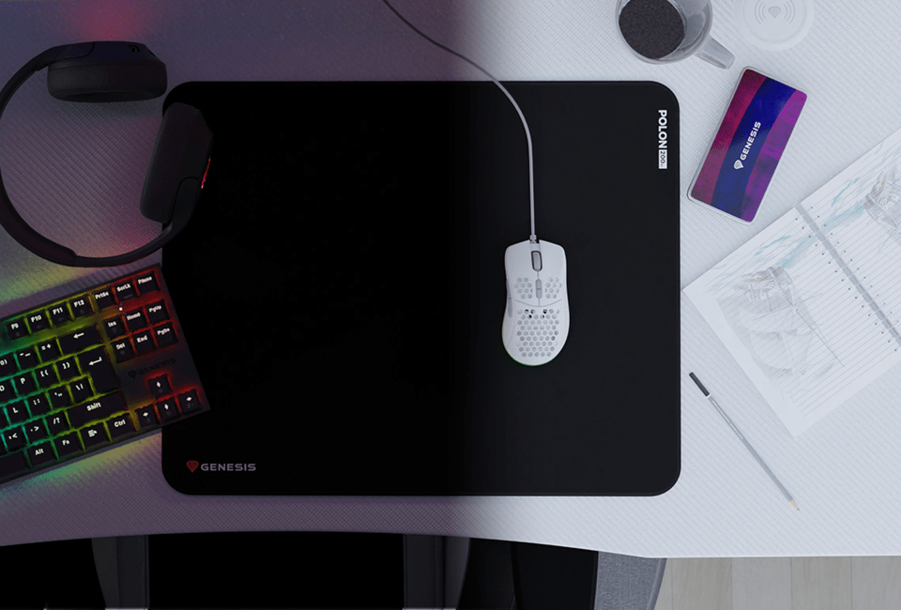 Large black mouse pad with a gaming mouse on it, surrounded by a keyboard, notebook, and a cup on a desk