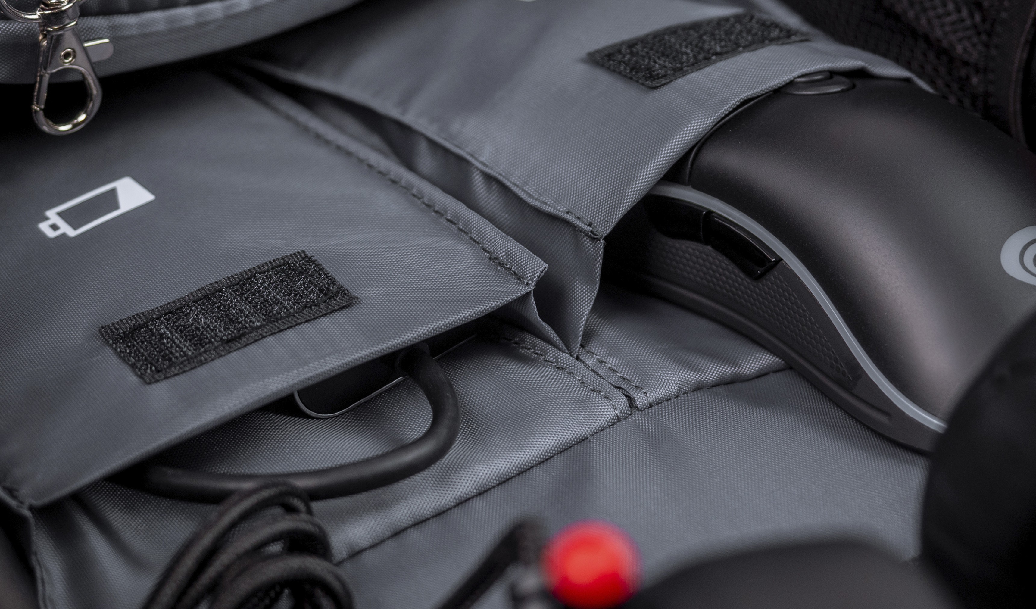 Gray interior of Genesis Pallad 550 backpack, showing compartments for a mouse and cables, with a battery icon visible
