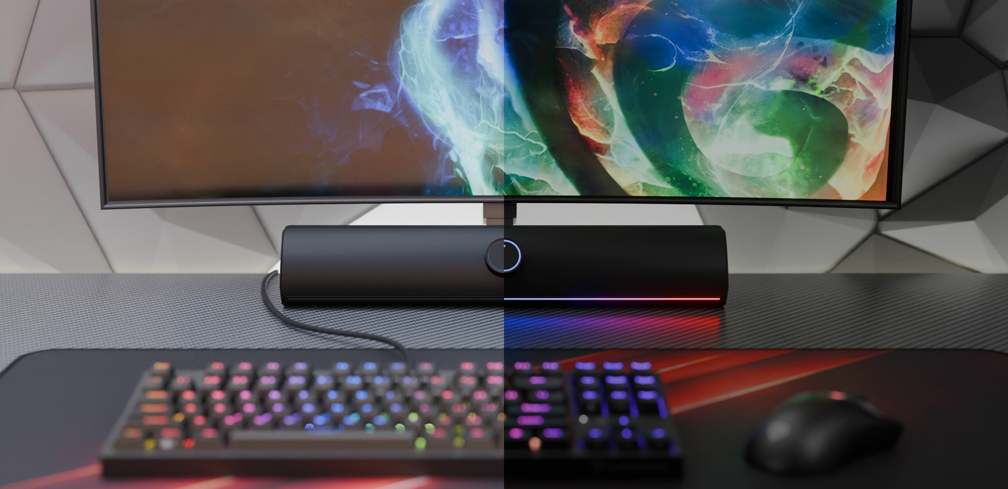 Black Bluetooth soundbar positioned below a colorful monitor, with a RGB gaming keyboard and mouse on a desk