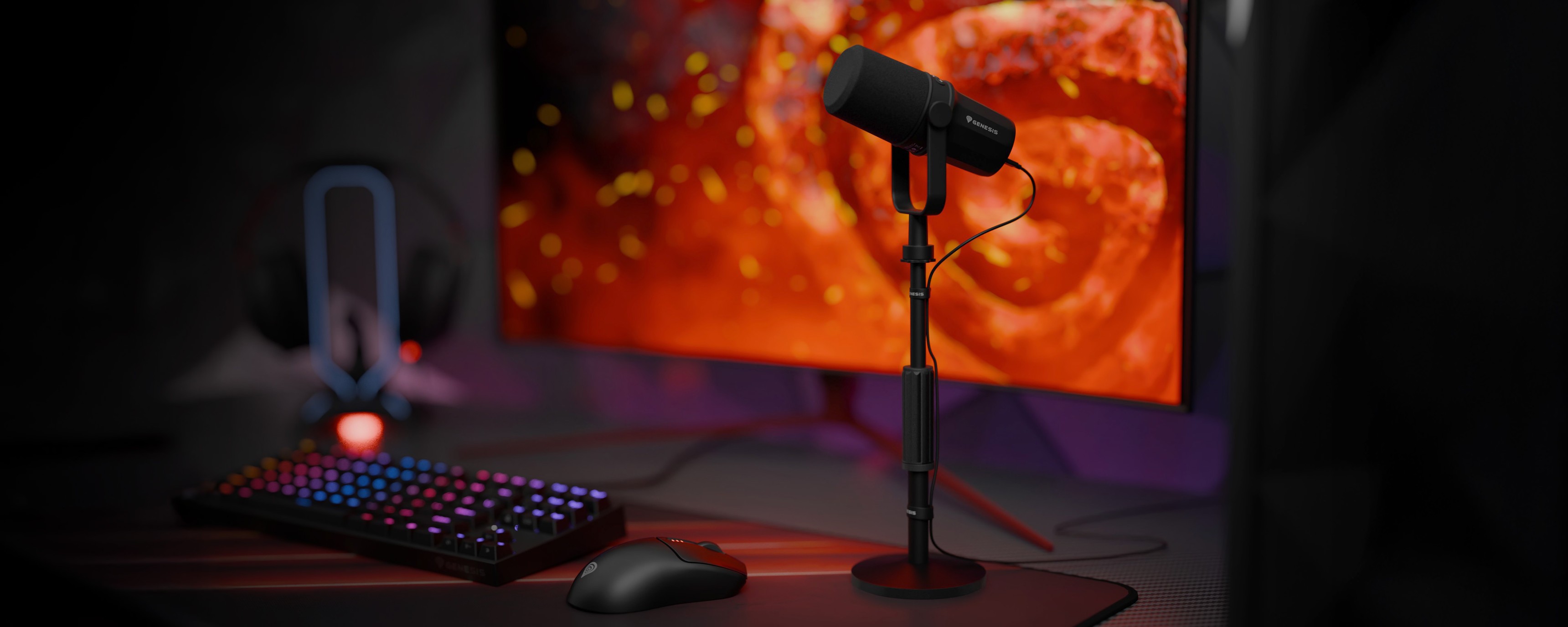 Desktop setup featuring a studio microphone on a stand, a colorful keyboard, mouse, and monitor