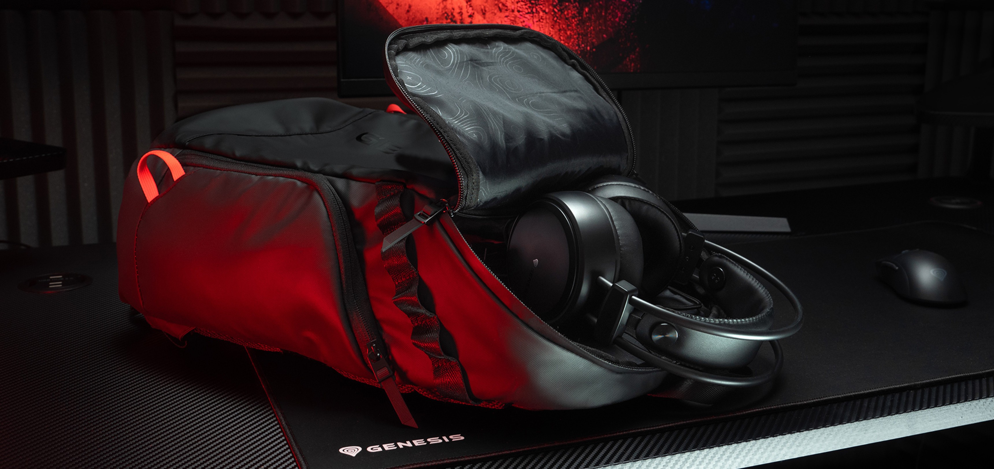 Black Genesis Pallad laptop backpack with a partially open compartment and headphones inside, set on a textured desk