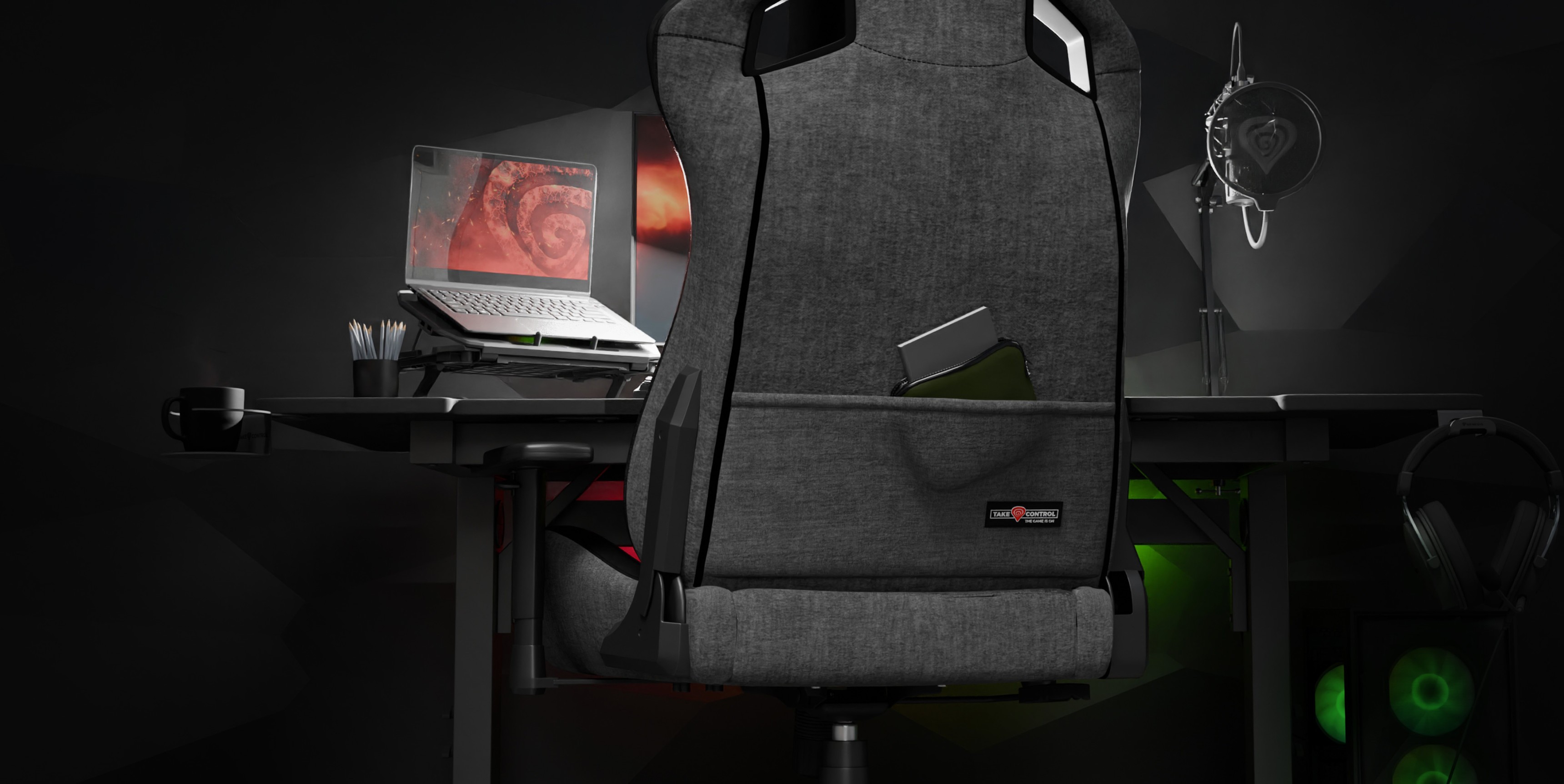 Gray Genesis Nitro 660 gaming chair positioned behind a desk with a laptop and gaming accessories in a dimly lit room