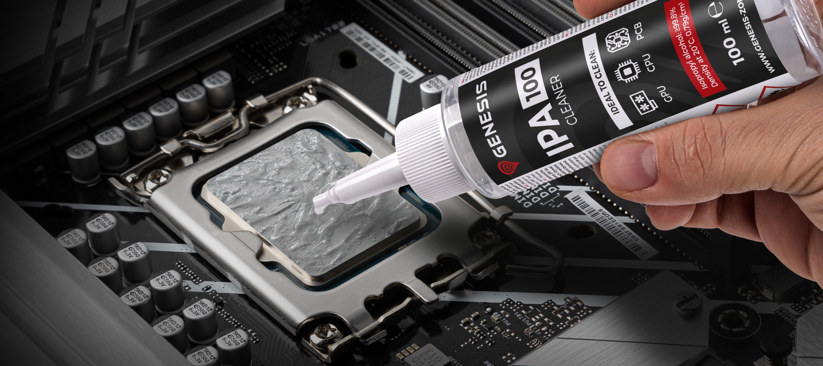 Hand holding a bottle of Genesis IPA 100 cleaner, applying it to a computer CPU socket on a motherboard