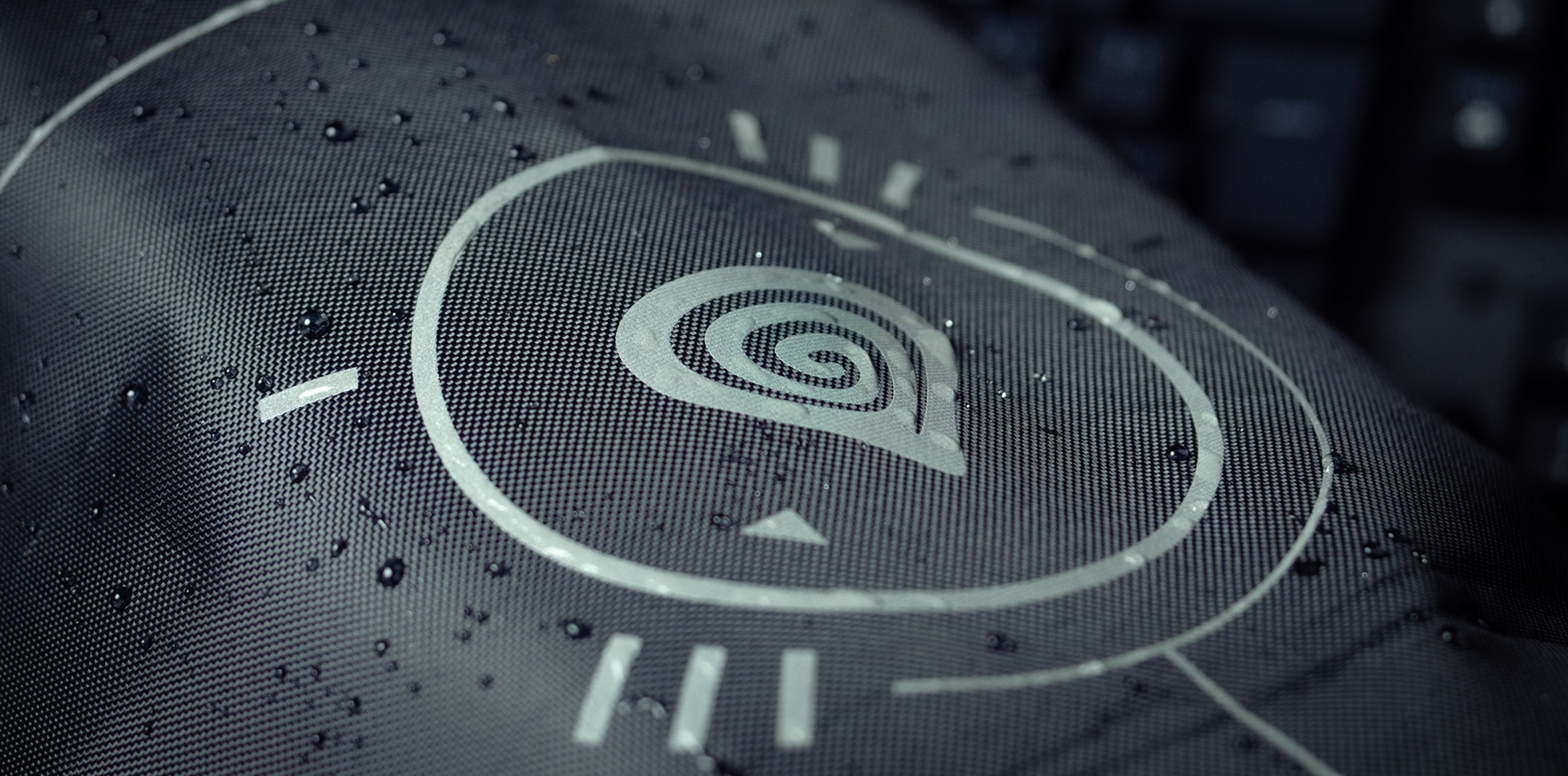 Close-up of the Genesis Bag G2 fabric showing a water-resistant design with a spiral logo and minimalistic lines