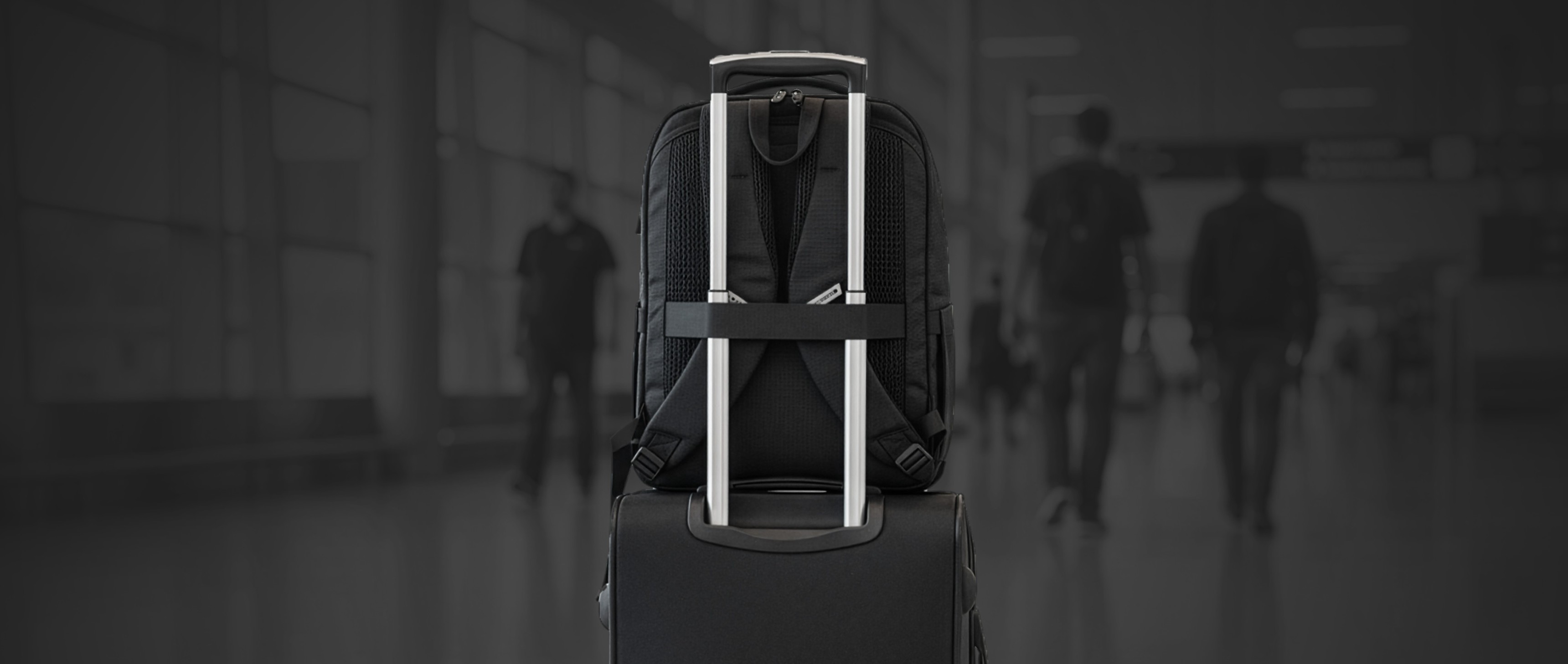 Black suitcase with a retractable handle in an airport setting with blurred travelers.