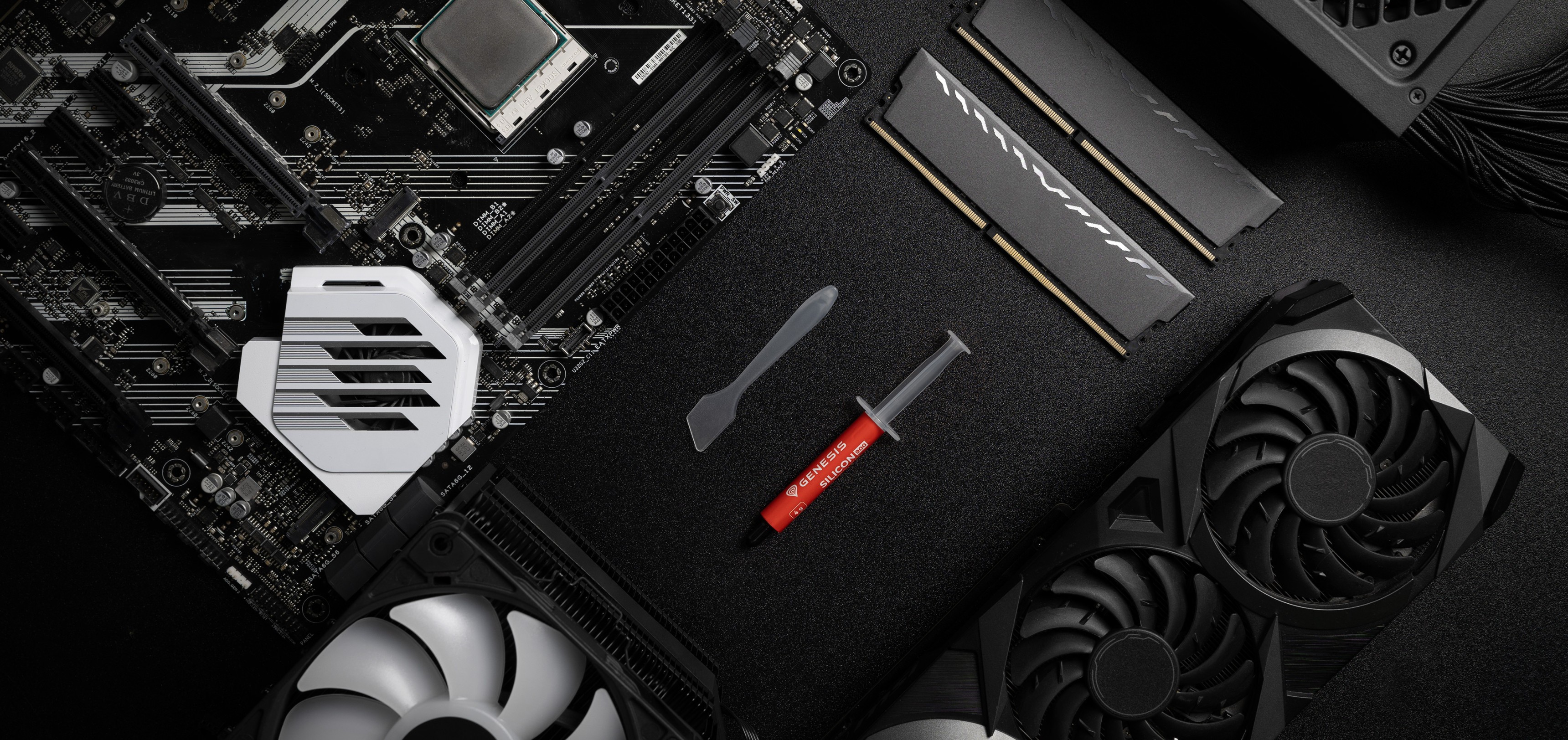 Thermal paste tube with a spatula, placed on a black background alongside a motherboard, RAM, and GPU