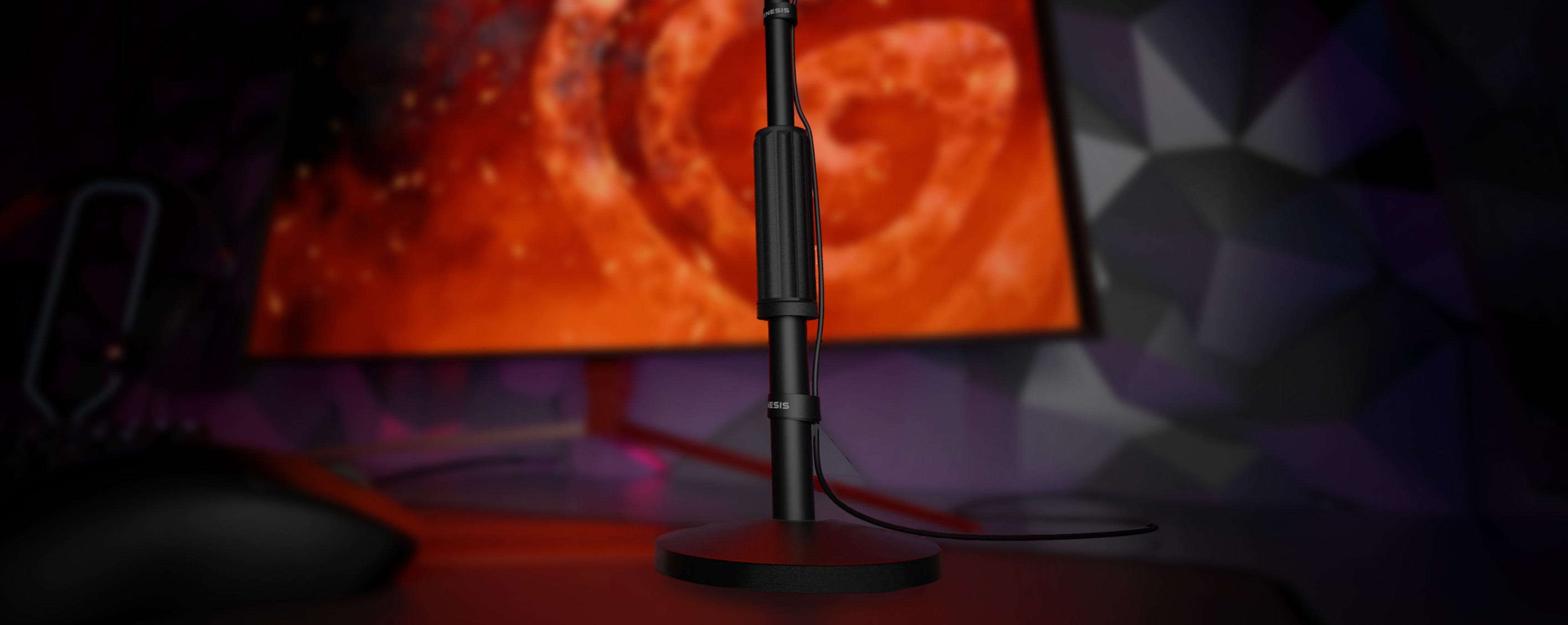 Black microphone on a sturdy stand with a connection cable, placed near a vibrant screen