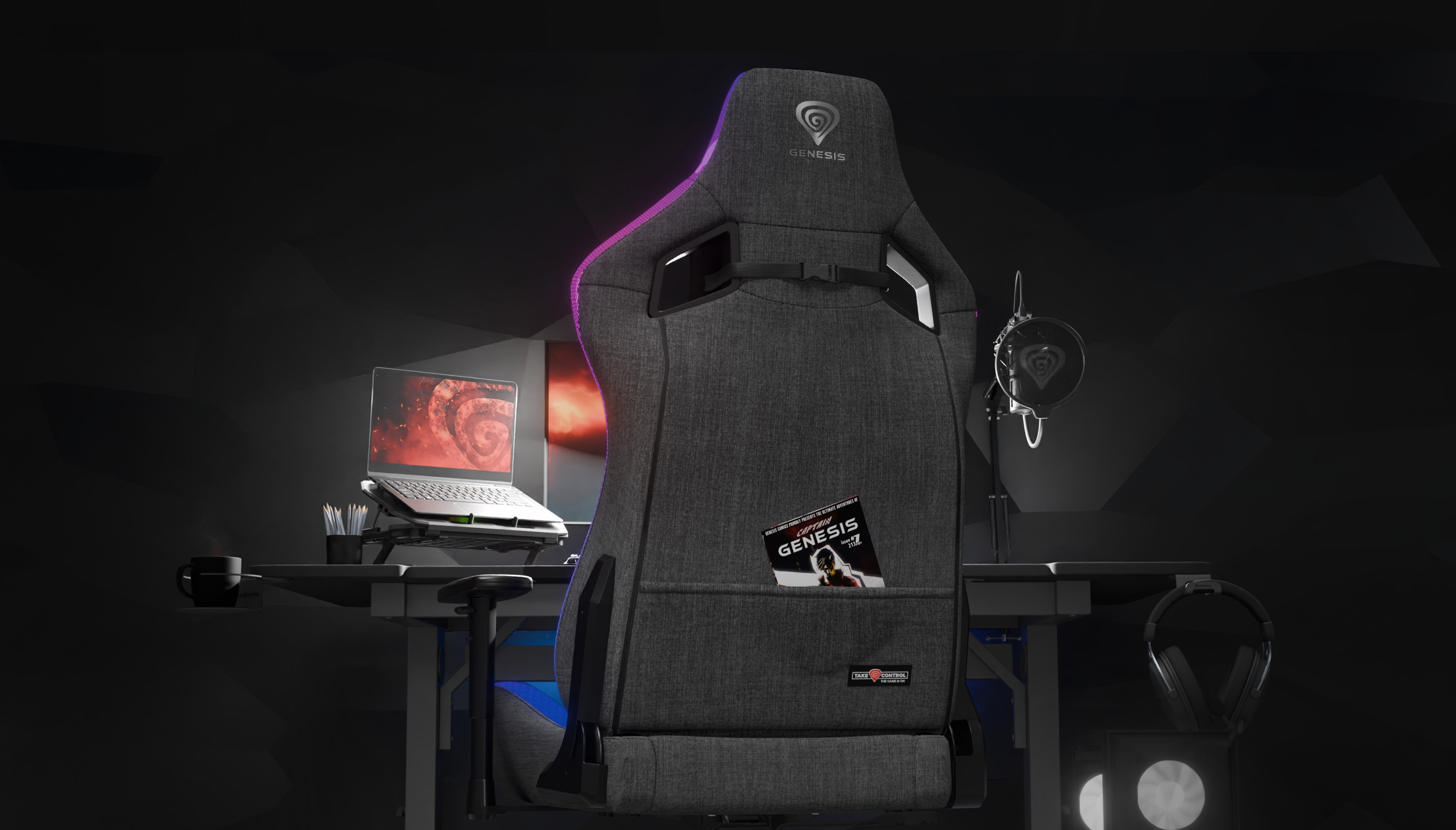 Gray gaming chair, Genesis Trit 660 RGB, positioned in front of a desk with a laptop and gaming accessories. RGB lighting accents visible