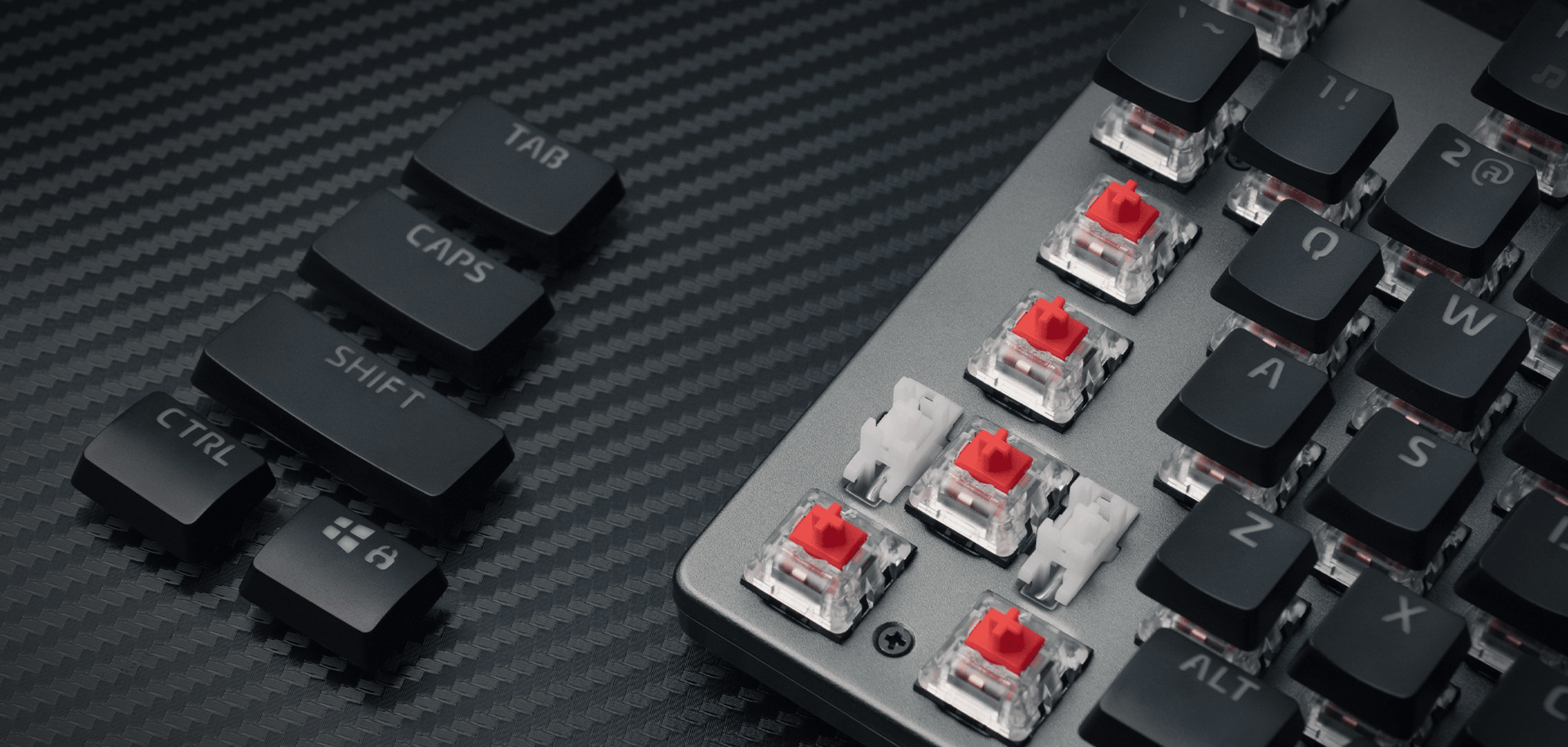 Close-up of a keyboard showing keys with red switches and some removed black keys.
