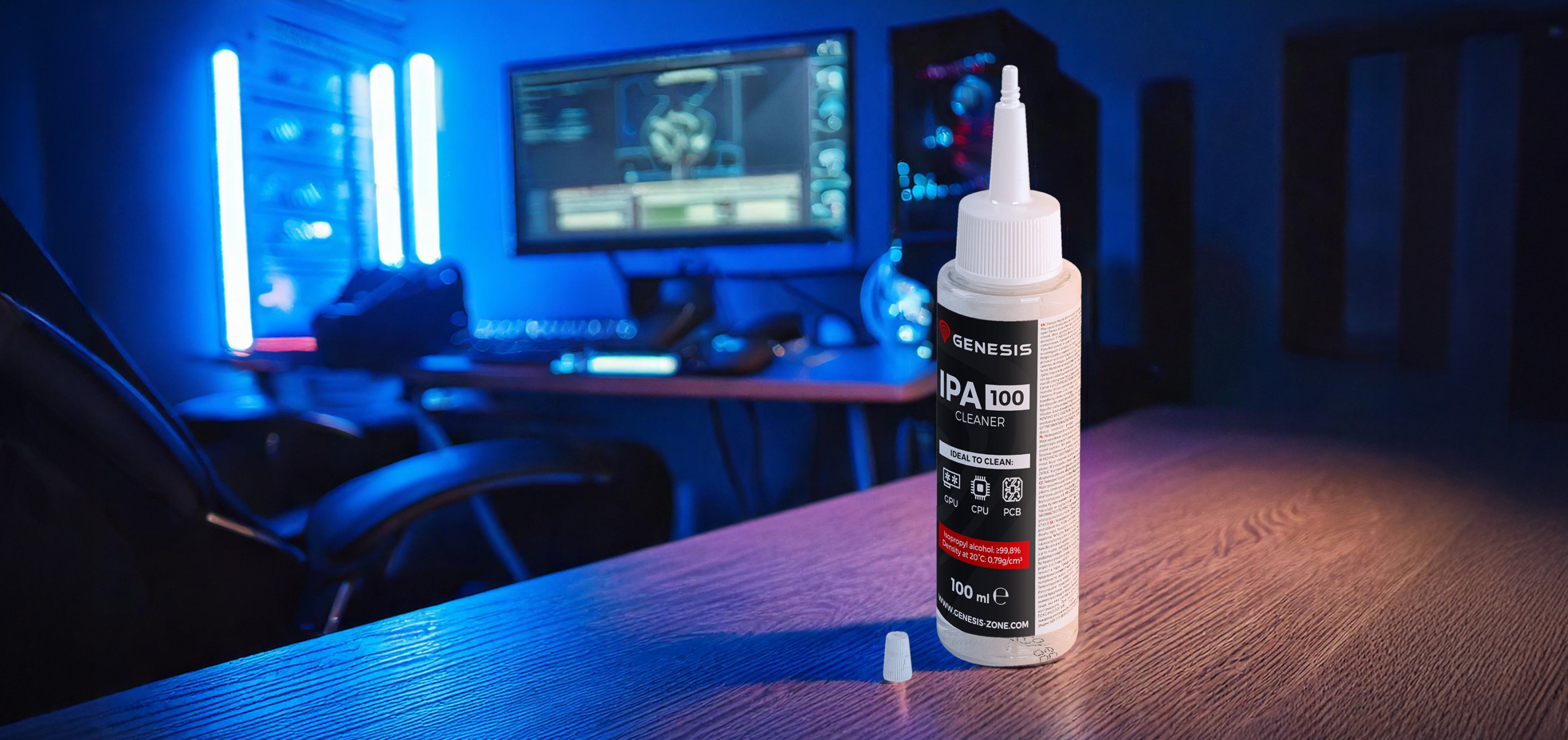Bottle of Genesis IPA 100 cleaner (100ml) on a wooden desk, with a gaming setup and blue ambient lights in the background
