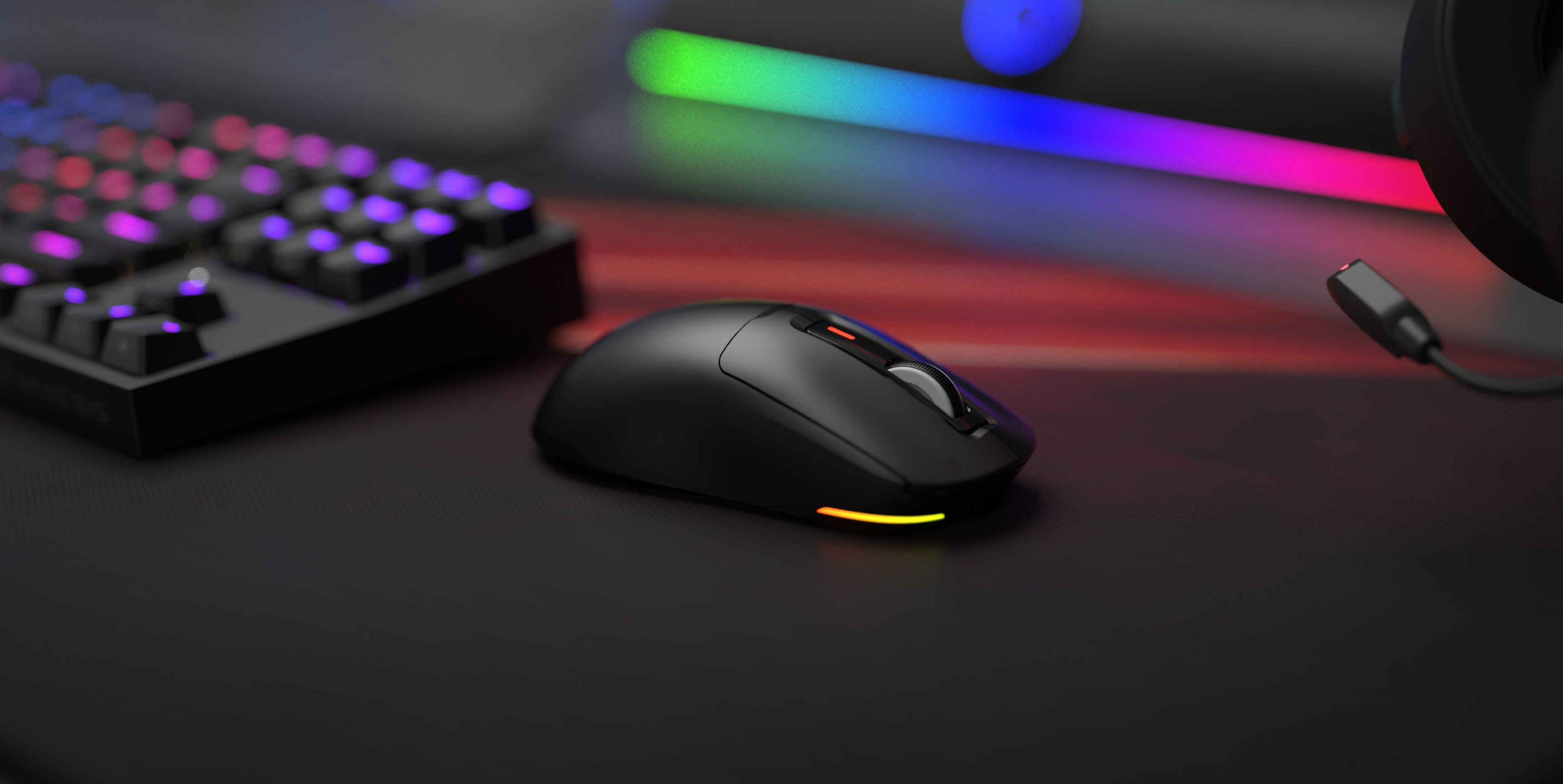 Black Genesis Zircon 660 wireless gaming mouse with RGB lighting, placed on a sleek gaming desk alongside a mechanical keyboard