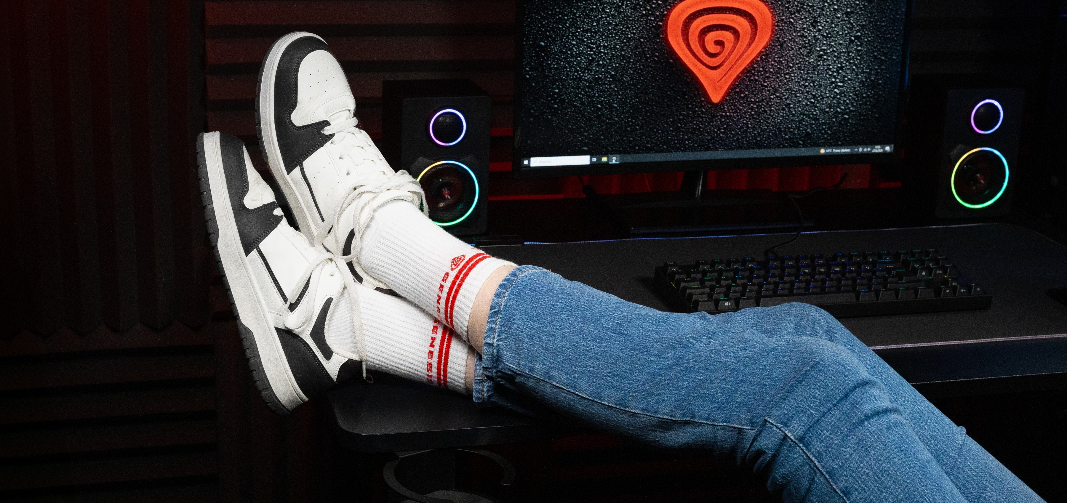 Sport socks in white with red stripes, worn with stylish sneakers, and blue jeans against a computer backdrop