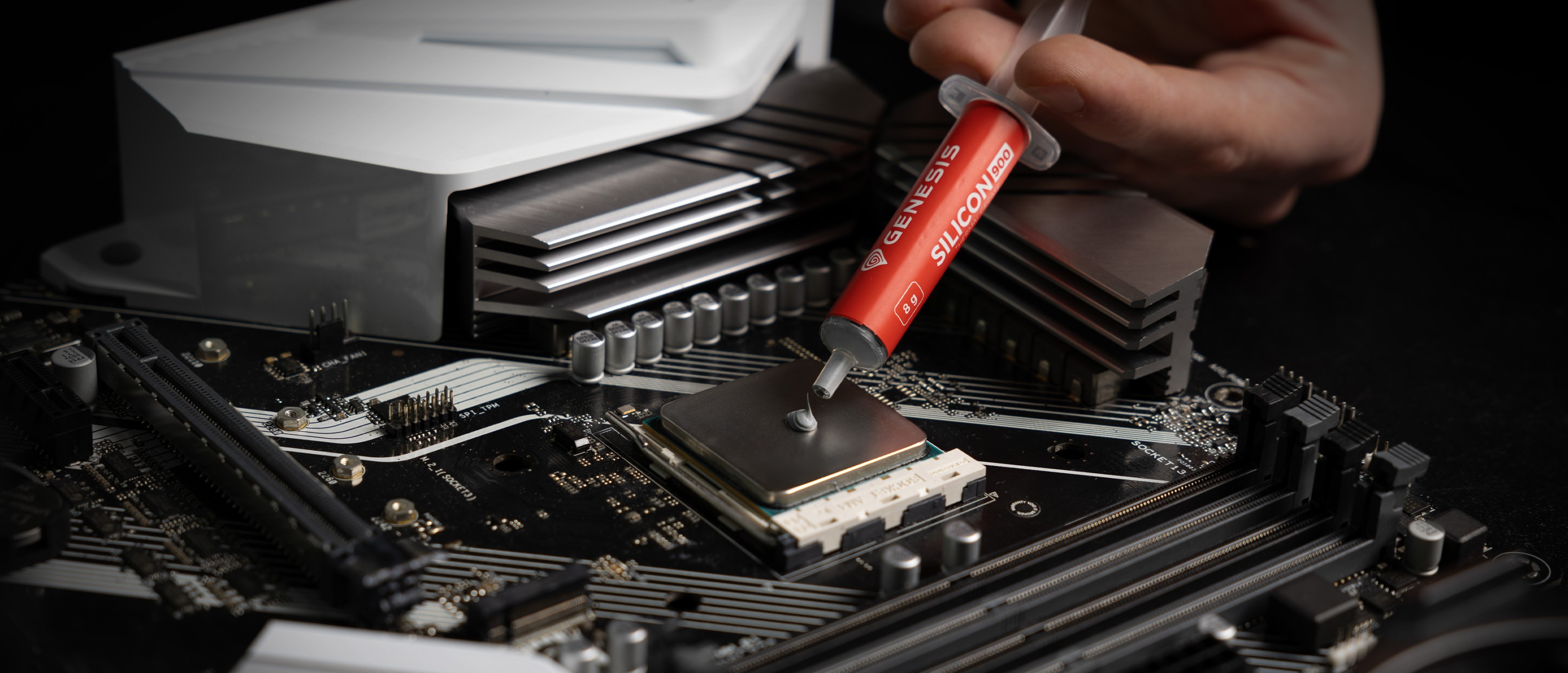 Syringe of Genesis Silicon thermal paste being applied to a CPU on a motherboard