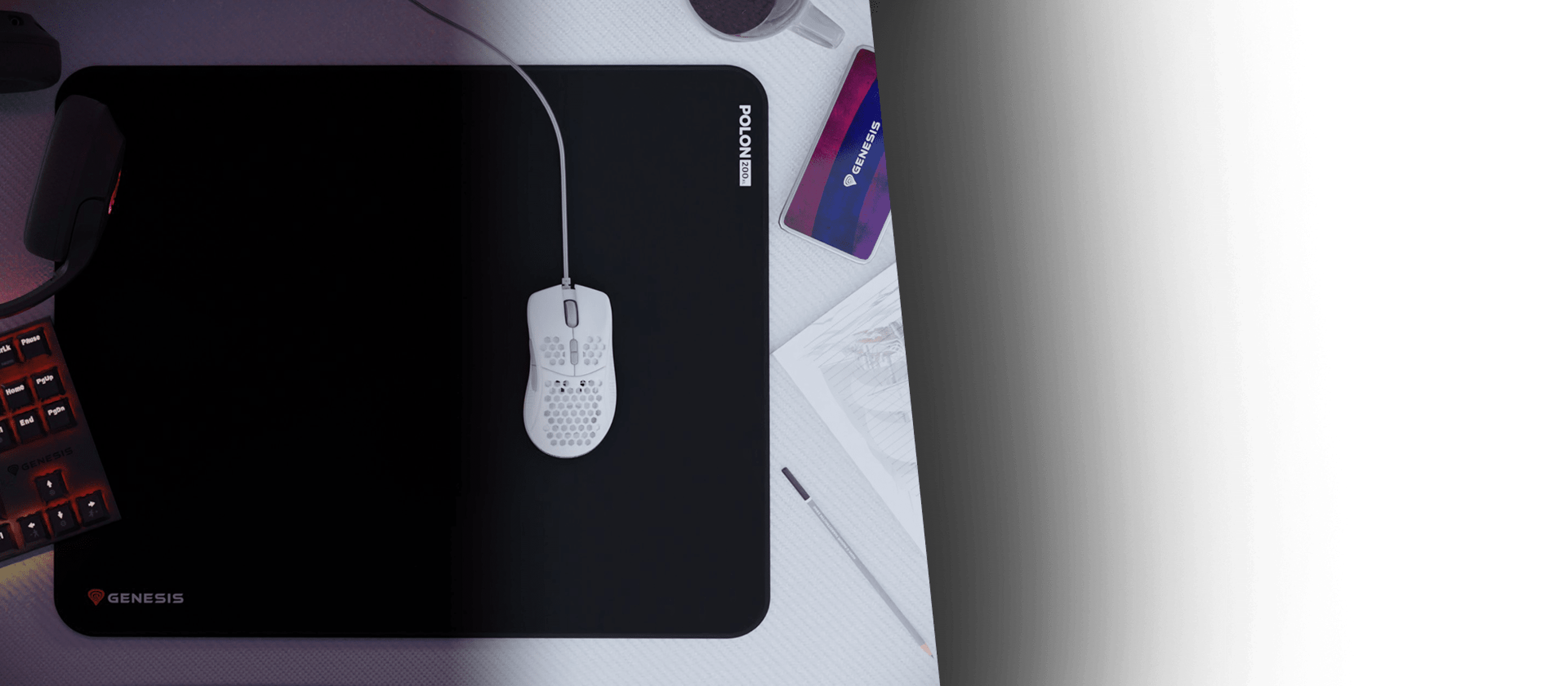 Large black mouse pad with a white mouse on it, featuring the Genesis logo. Other gaming accessories are visible in the background