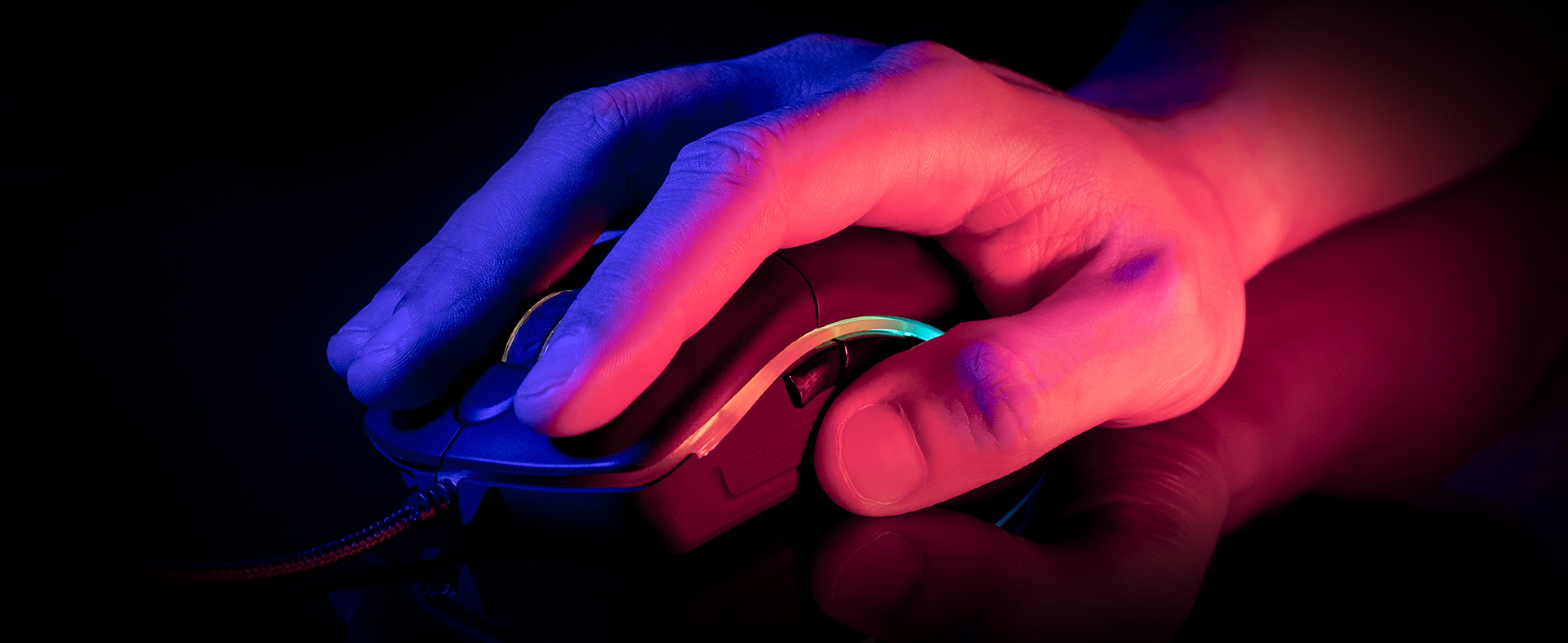 Close-up of a hand using a black gaming mouse with RGB lighting, suitable for gamers, showcasing ergonomic design and precision
