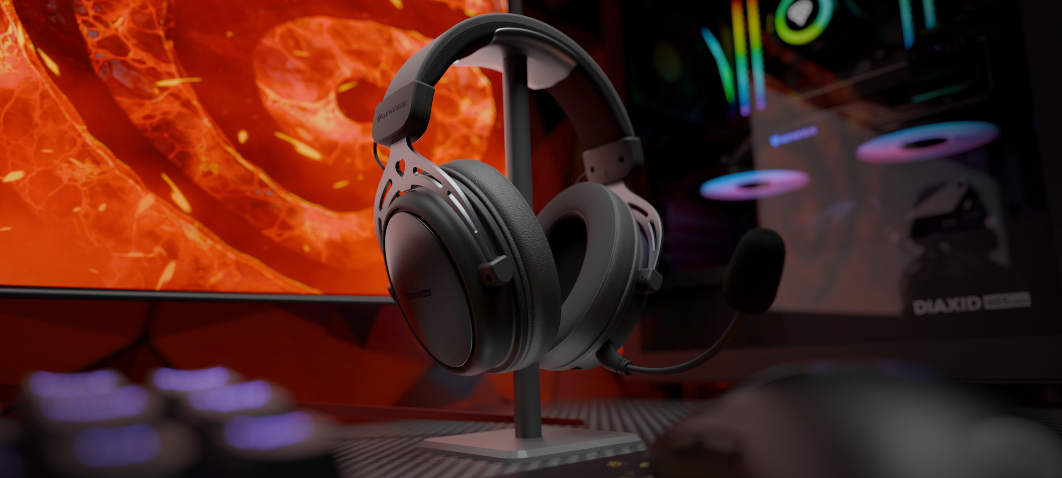 Black wireless over-ear headphones with a microphone, displayed beside a computer monitor